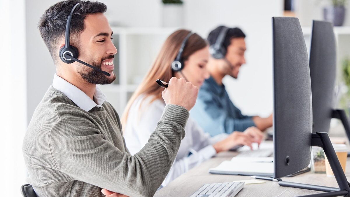 Tech support talking to client over headset while looking at computer.