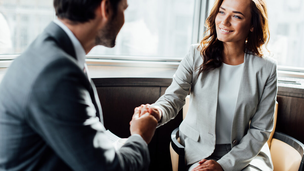 Selective focus of happy businesswoman shaking hands with businessman