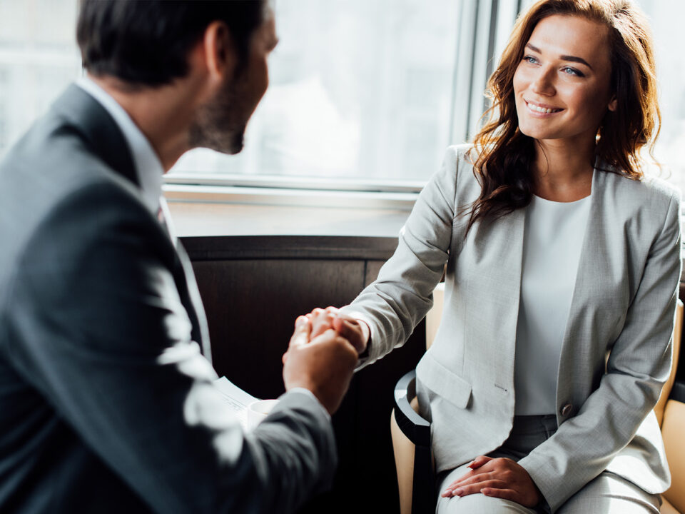 Selective focus of happy businesswoman shaking hands with businessman