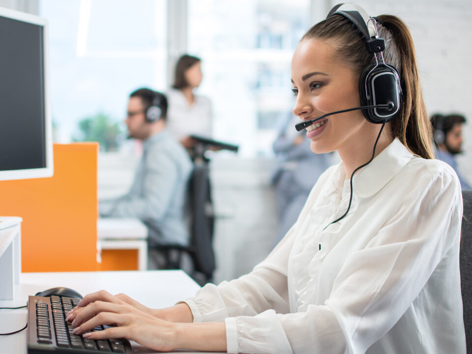 Friendly customer support operator with headset and microphone assisting to client in call centre